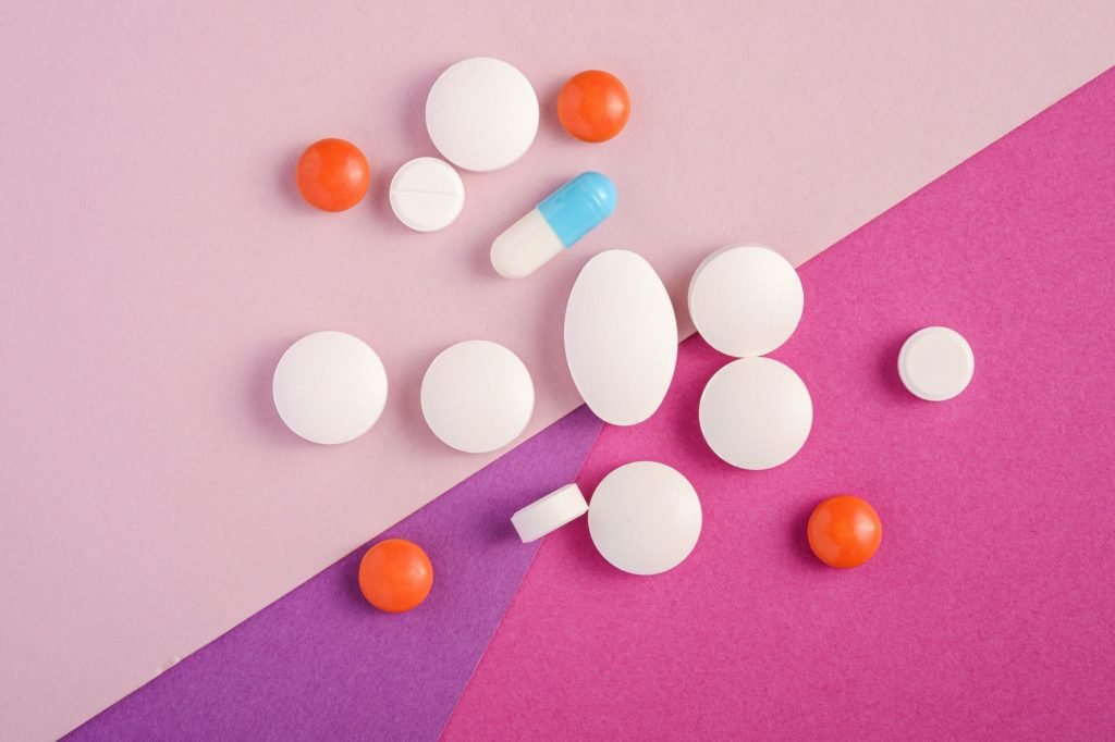 Pills and tablets on pink background, healthcare medical concept, antibiotics and cure