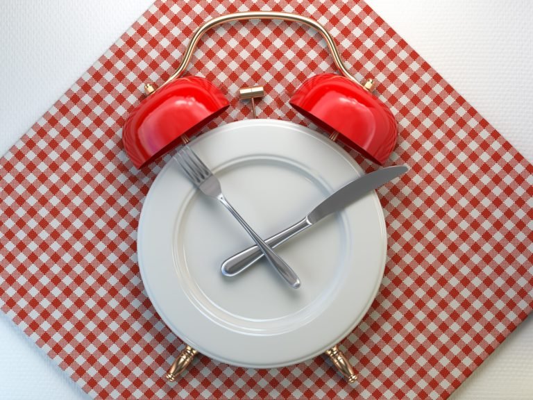 Plate as alarm clock with knife and fork in a restaurant. Time to eat, intermittent fasting